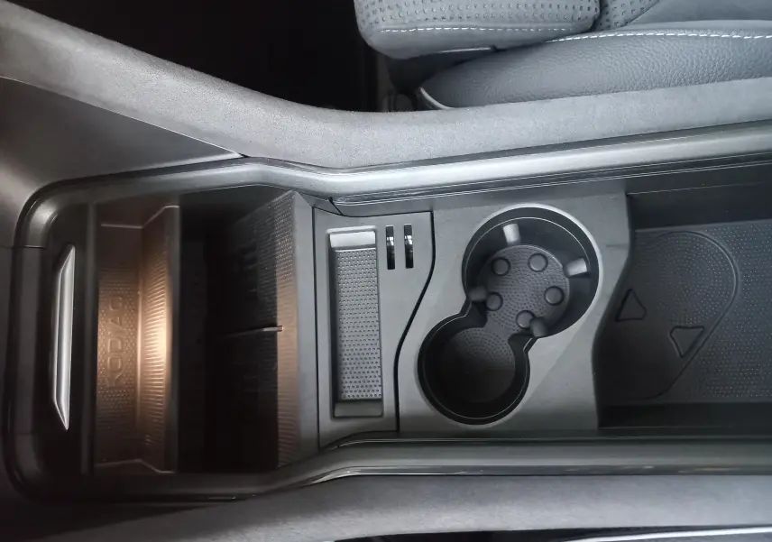 Vue plongeante sur la console centrale noire du Skoda Kodiaq 2024 avec porte-gobelets et rangement marqué KODIAQ.