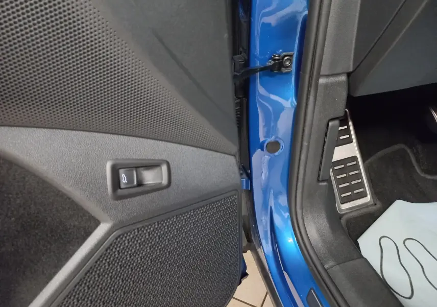 Détail de l’ouverture de porte côté conducteur d’un Skoda Kodiaq Bleu RS 2024 avec bouton de coffre et pédalier en aluminium.