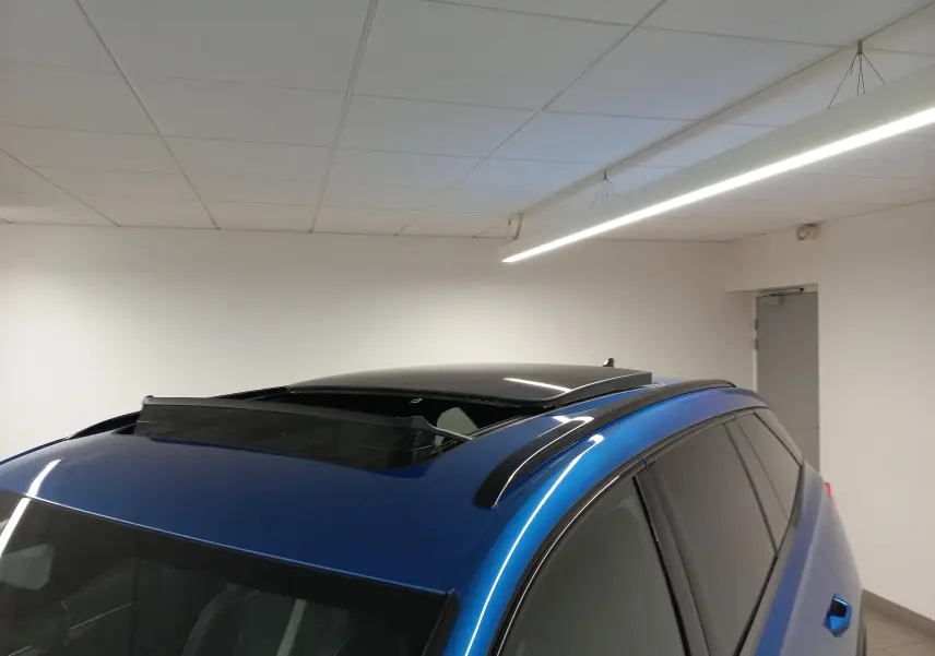 Vue en plongée du toit panoramique ouvert du Skoda Kodiaq Bleu RS avec barres de toit noires et vitres teintées.