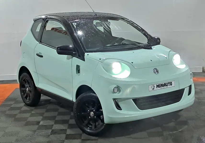 Vue 3/4 avant d'une Aixam Minauto E chic électrique 2026 vert clair avec toit noir et jantes noires.