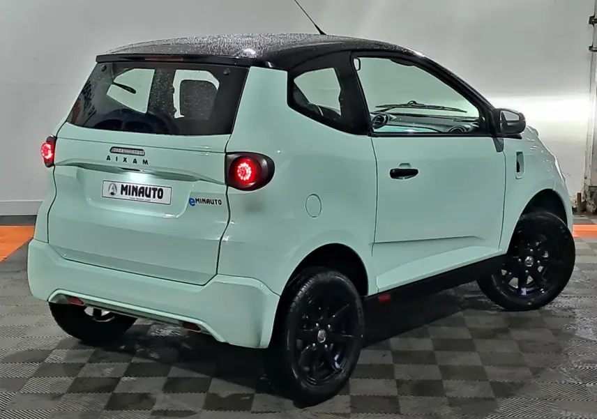 Vue 3/4 arrière droite de l'AIXAM MINAUTO E chic 2026 vert avec rétroviseur caméra côté conducteur et jantes noires.