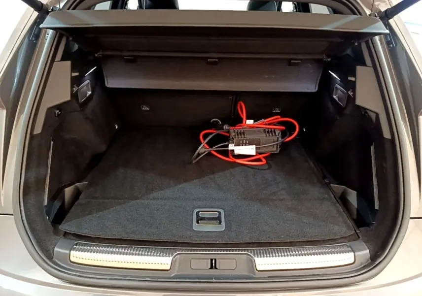 Coffre ouvert vu de l'arrière d'un DS7 Crossback gris foncé avec câble de recharge rouge visible à l'intérieur.