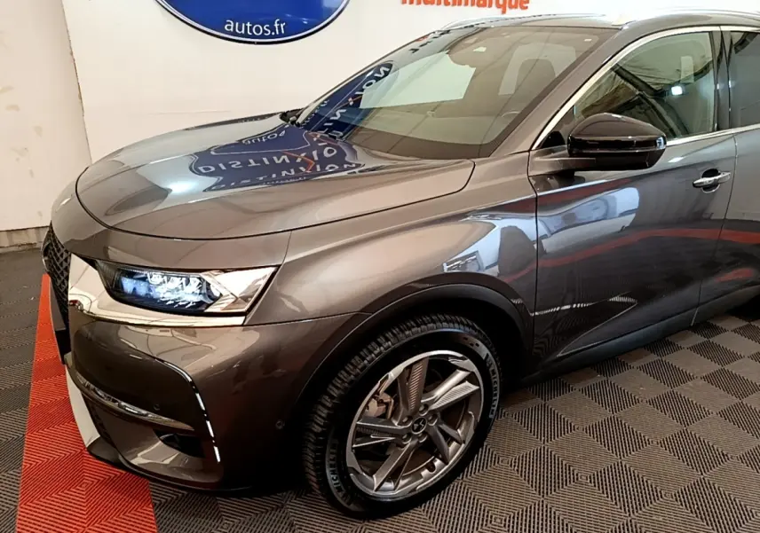 Vue 3/4 avant droit du DS7 Crossback E-TENSE 4x4 gris foncé avec phares LED allumés et jantes alliage distinctives.