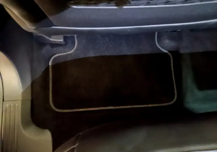 Tapis de sol noir avec surpiqûres blanches dans l'habitacle d'un DS7 Crossback gris foncé, vue intérieure au sol côté passager.