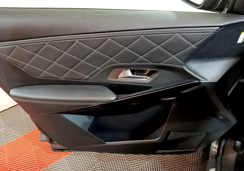 Gros plan sur la porte intérieure côté droit du DS7 Crossback gris foncé, avec surpiqûres losanges et poignée métal.