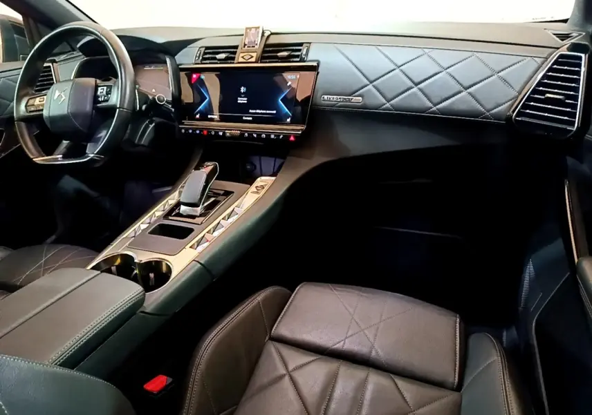 Vue intérieure côté conducteur du DS7 Crossback E-TENSE 4x4 300 Rivoli 2021, tableau de bord cuir matelassé noir et écran tactile central.