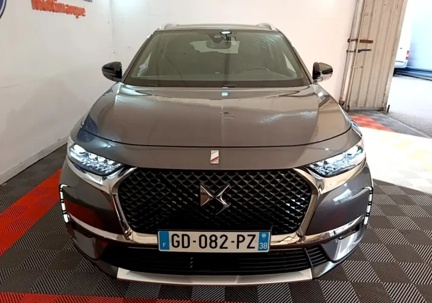 Vue frontale d'un DS7 Crossback E-TENSE 4x4 gris foncé avec calandre noire et phares LED allumés.