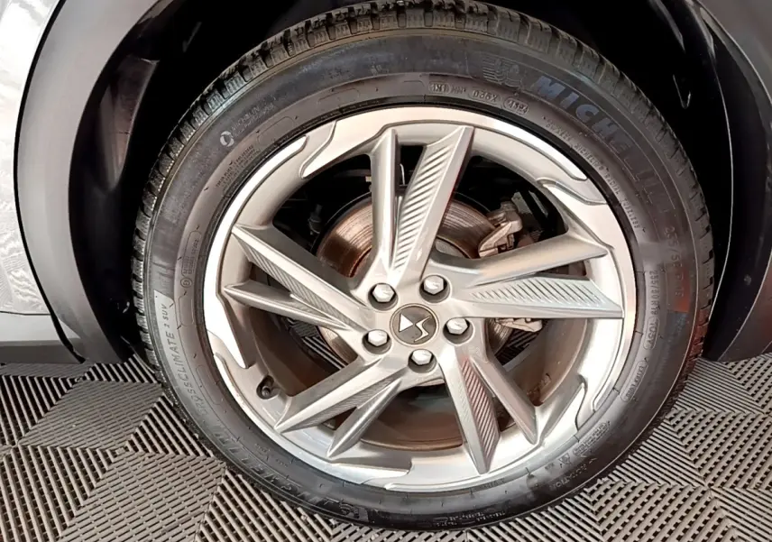Gros plan sur la jante en alliage argentée du DS7 Crossback gris foncé, mettant en valeur le logo DS central.