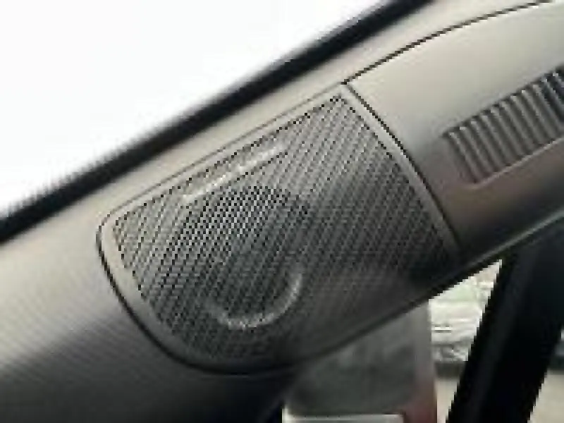 Gros plan sur l'enceinte Bose intégrée dans l'habitacle du Renault Captur rouge 2025, côté avant droit.