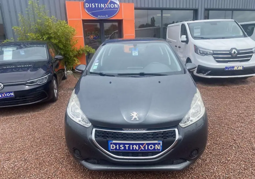 Vue frontale d'une Peugeot 208 gris shark 2013 avec calandre chromée et logo lion visible sur le capot.