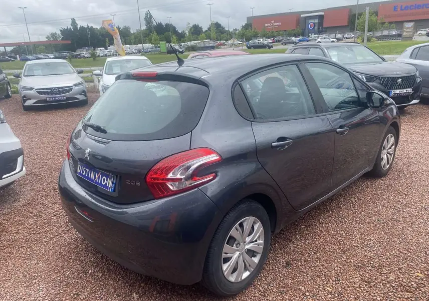 Peugeot 208 gris shark vue 3/4 arrière droit sur parking, avec feux arrière et antenne de toit visibles.