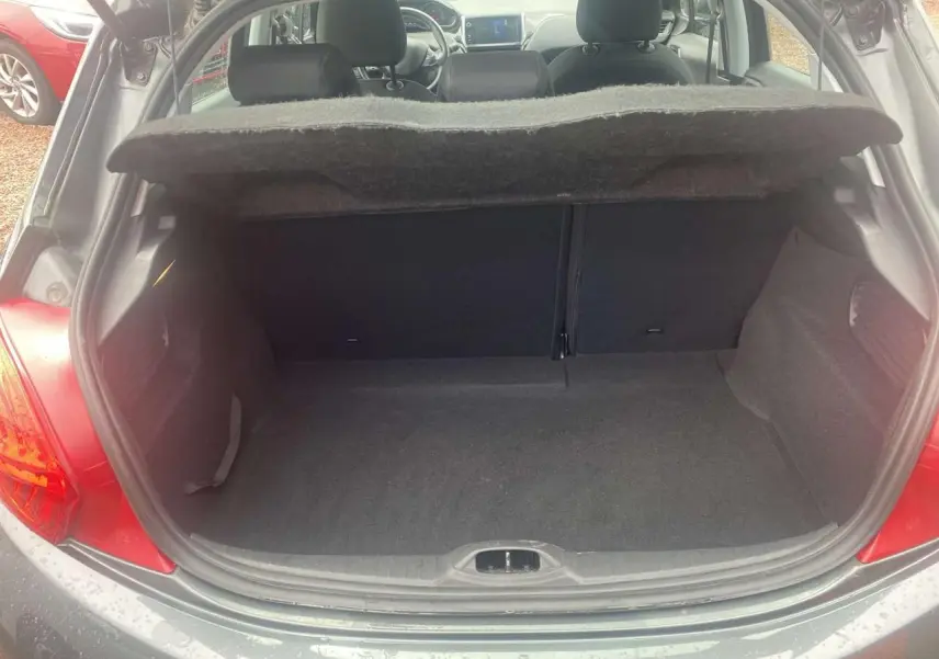 Coffre ouvert d'une Peugeot 208 gris shark, vue arrière montrant l'intérieur spacieux et la plage arrière relevée.