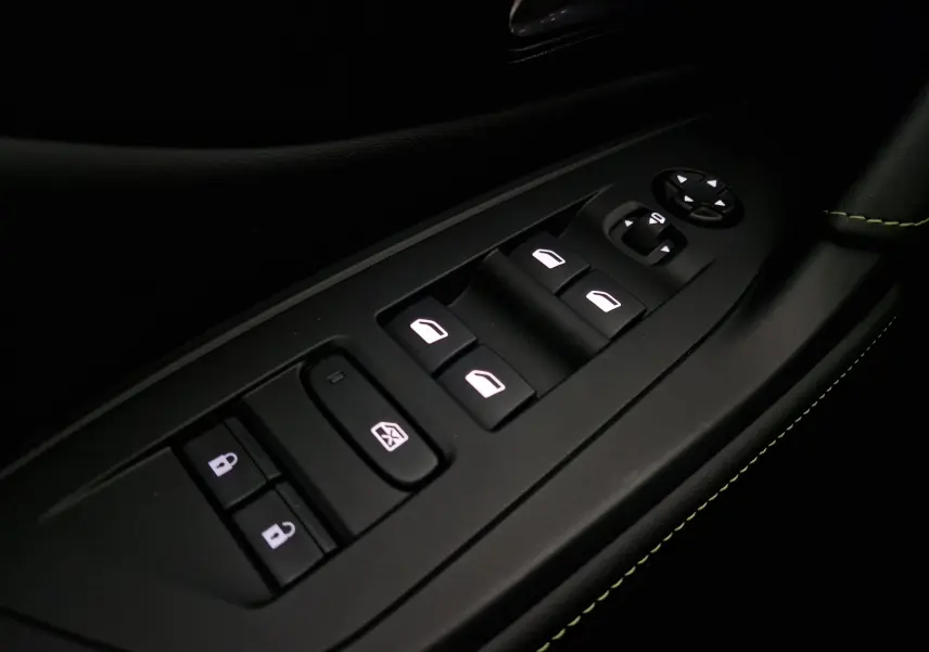 Gros plan sur les commandes de lève-vitres et rétroviseurs côté conducteur d'une Peugeot 308 GT+ blanc Okenite, avec surpiqûres vertes.