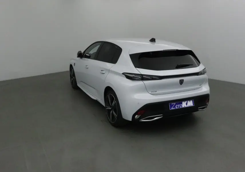 Peugeot 308 blanc Okenite vue 3/4 arrière droit dans un studio, avec vitres teintées et jantes alliage noires.