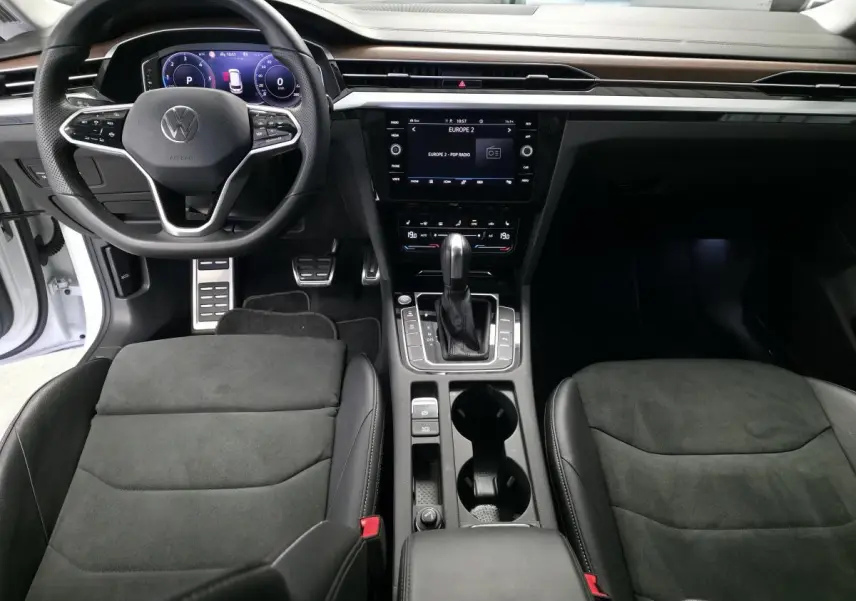 Intérieur avant de la Volkswagen Arteon 2024, vue centrée sur le tableau de bord et la console avec sellerie noire et volant multifonction.