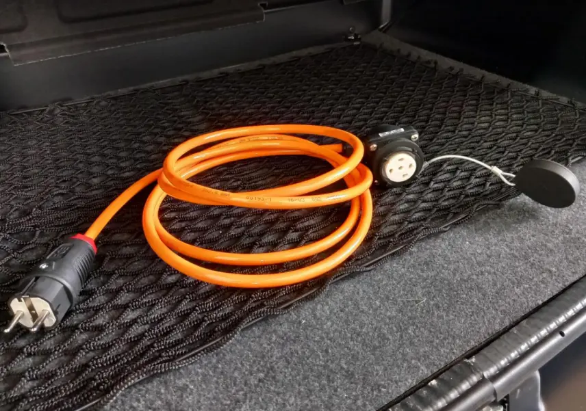 Câble de recharge orange enroulé dans le coffre d'une Aixam Mega E-Scouty Evo bleu électrique, vue intérieure arrière.