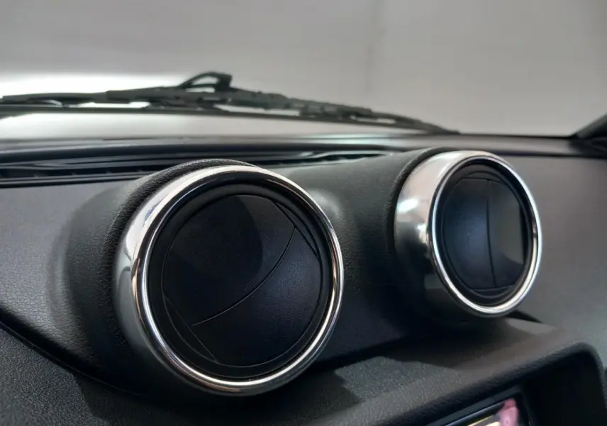 Gros plan sur les aérateurs ronds chromés du tableau de bord de l'AIXAM MEGA bleu électrique 2026.