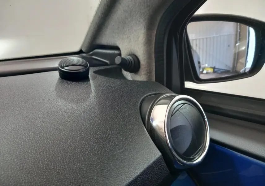 Détail intérieur côté conducteur de l'AIXAM MEGA bleu 2026, avec aérateur rond chromé et rétroviseur extérieur caméra.