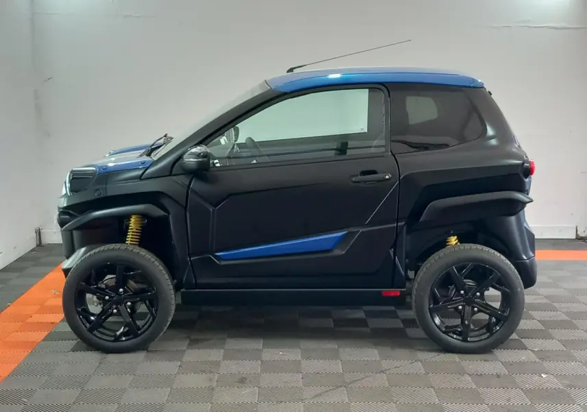 Vue de profil côté gauche d'une Aixam MEGA E-Scouty Evo 2026 bleu et noir avec suspensions jaunes et jantes noires.