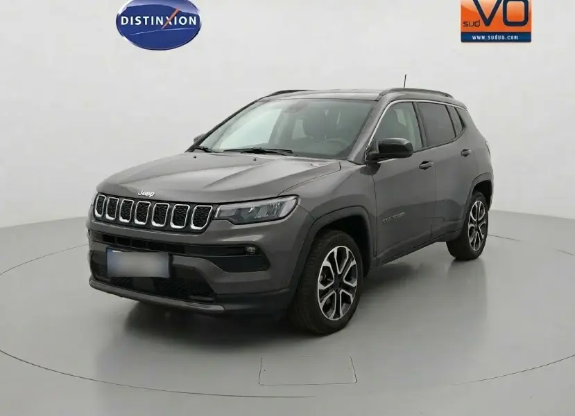 Jeep Compass gris 3/4 avant droit, jantes alliage 18 pouces, calandre distinctive et rétroviseurs noirs.