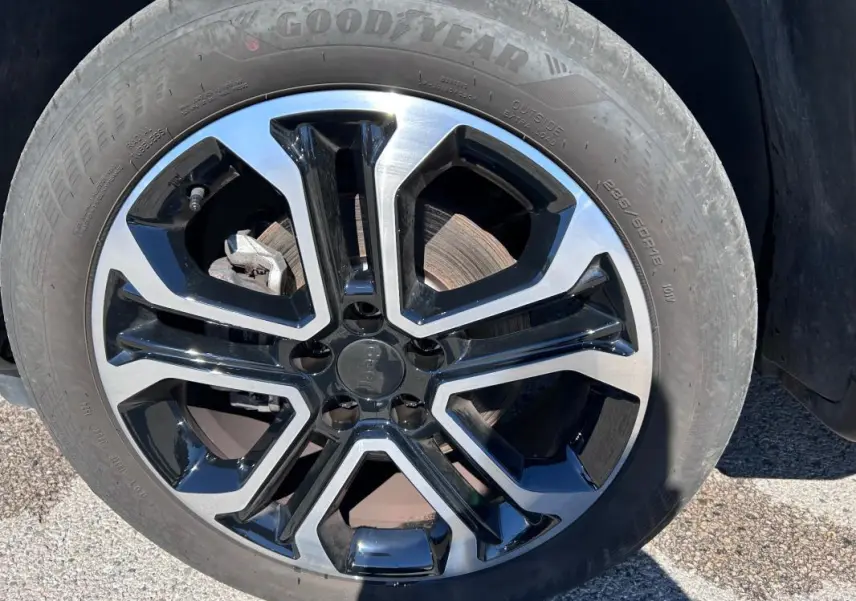 Gros plan sur la jante alliage 18 pouces noire et argentée du Jeep Compass gris 2024, pneu Goodyear visible.