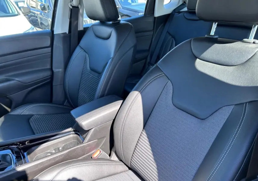 Vue intérieure rapprochée des sièges avant noirs en cuir du Jeep Compass 2024, avec accoudoir central visible.