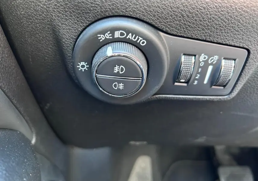 Gros plan sur le bouton de commande des phares avec réglages automatiques dans l'habitacle du Jeep Compass gris 2024.
