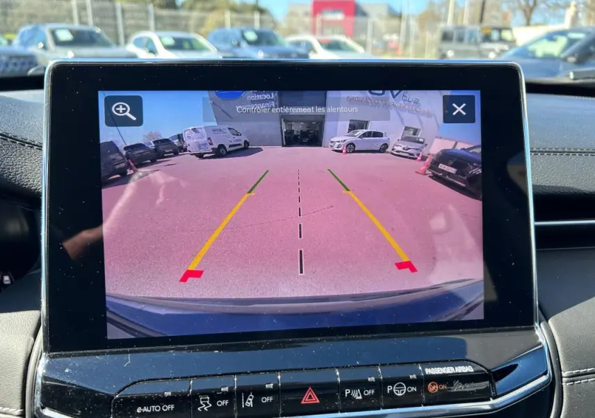 Écran tactile affichant la caméra de recul du Jeep Compass gris, vue arrière avec lignes de guidage colorées.