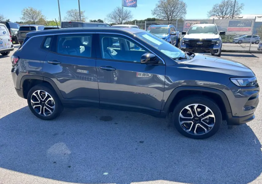 Vue de profil côté gauche d’un Jeep Compass gris 2024 avec jantes alliage 18 pouces sur parking extérieur.