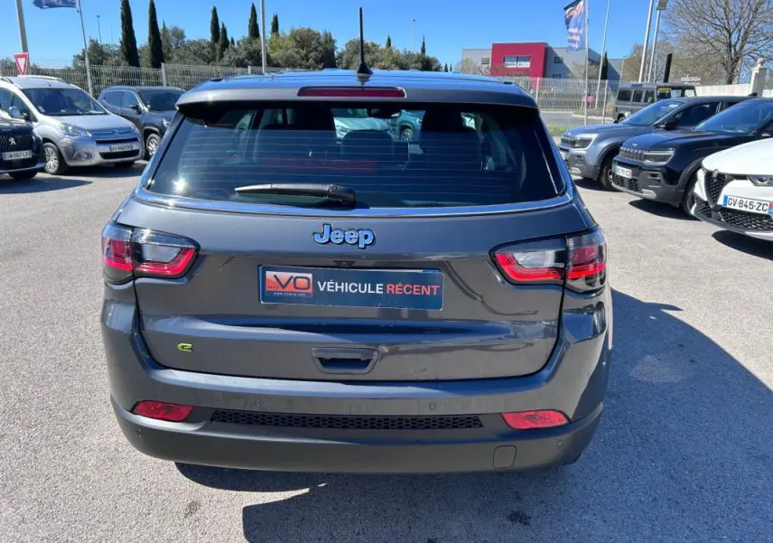 Vue arrière d'un Jeep Compass gris 2024 avec feux LED et logo Jeep bien visible sur un parking.
