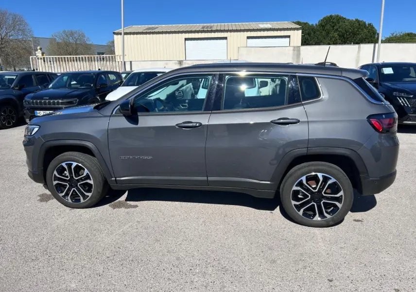 Vue de profil côté gauche d’un Jeep Compass gris 2024 avec jantes alliage 18 pouces et toit contrasté noir.