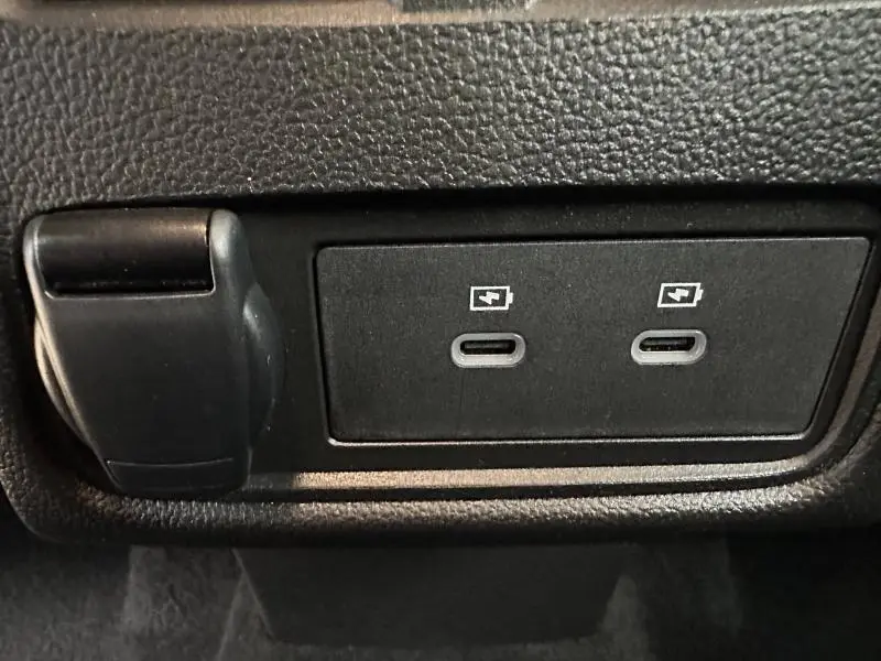 Gros plan sur deux ports USB-C de recharge rapide noirs dans l'habitacle du Renault Captur rouge 2025.