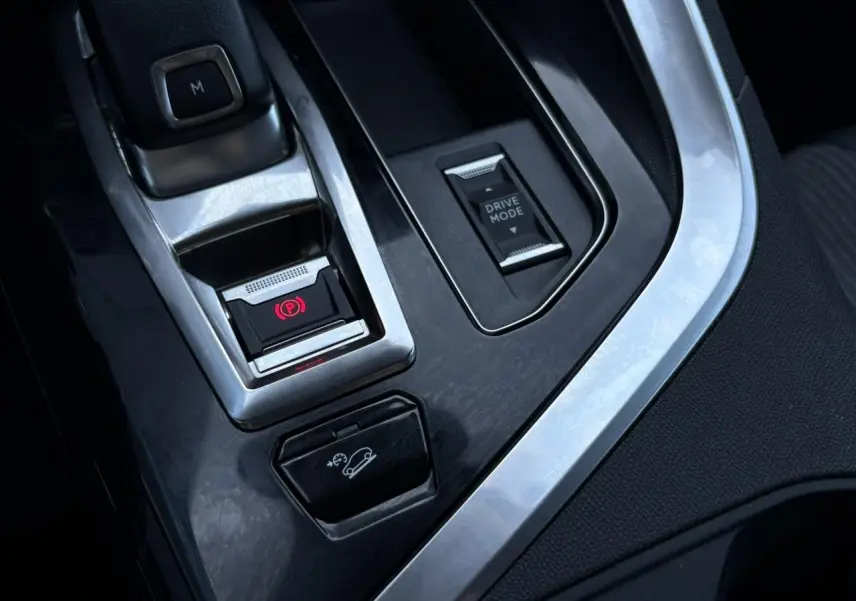 Gros plan sur la console centrale du Peugeot 5008 gris Platinium montrant le frein à main électrique et le bouton Drive Mode.