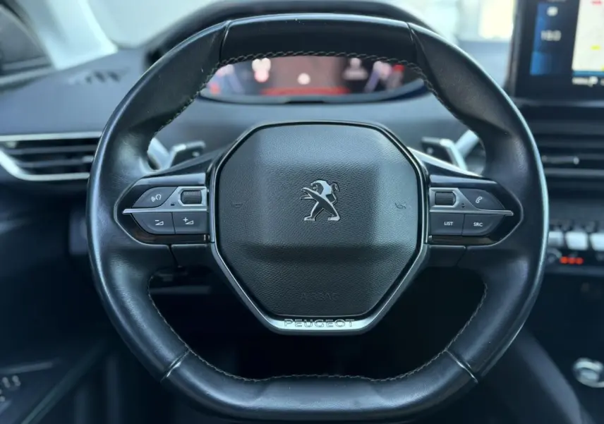 Volant cuir noir Peugeot 5008 2022 vu de face avec commandes intégrées et logo central argenté.