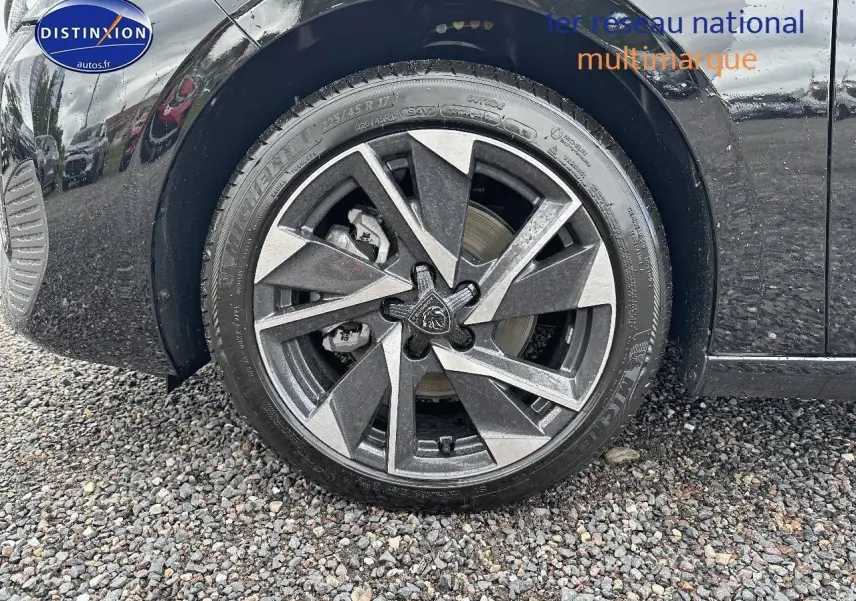 Gros plan sur la jante alu noire et grise du côté avant gauche d'une Peugeot 308 noire 2025.