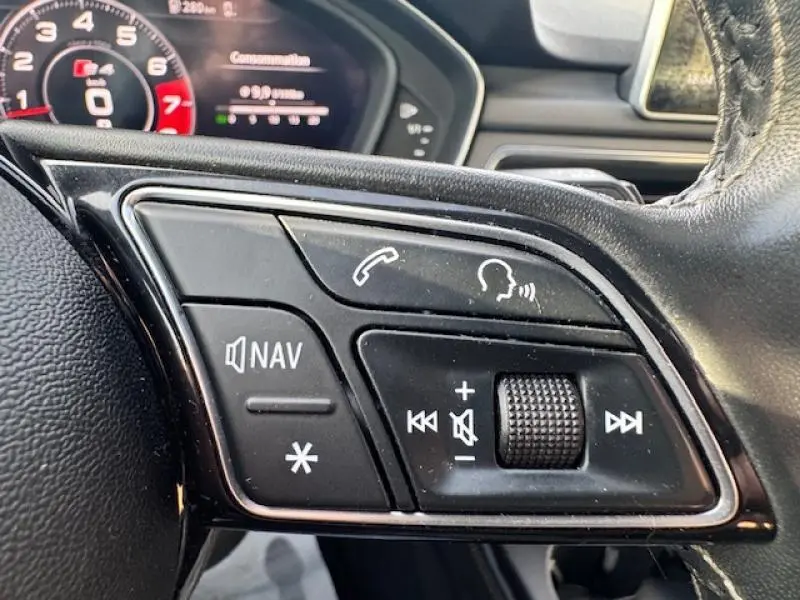 Gros plan sur les commandes audio et vocales au volant cuir noir de l'Audi S4 Avant 2017, tableau de bord partiellement visible.