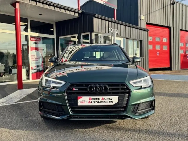 Audi S4 Avant Vert Gotland vue de face, avec calandre noire et phares LED distinctifs, devant un garage rouge et noir.