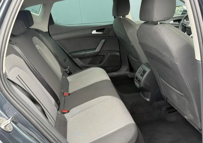 Vue intérieure arrière côté gauche du SEAT Leon 2025, montrant les sièges tissu bicolores et les vitres surteintées.