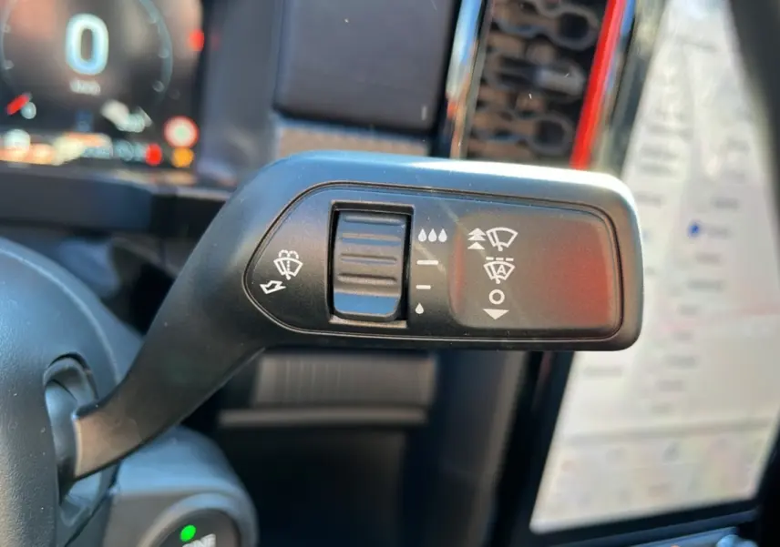 Gros plan sur la commande des essuie-glaces dans l'habitacle du Ford Ranger Raptor gris commandeur, avec écran tactile en arrière-plan.