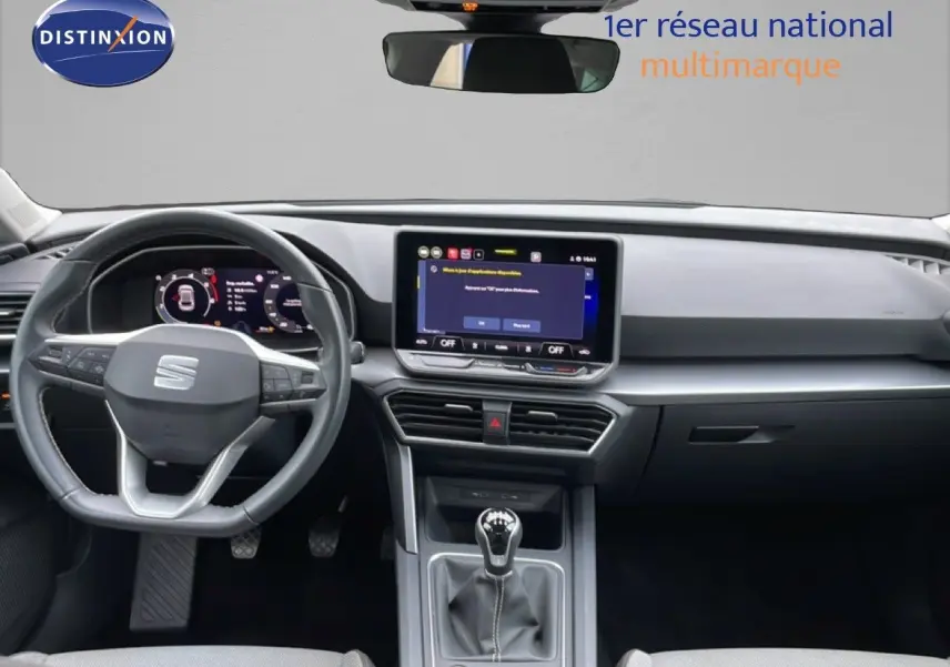 Vue intérieure frontale du tableau de bord gris noir de la SEAT LEON 2025 avec écran tactile et boîte manuelle.