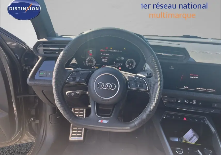 Vue intérieure centrée sur le volant S-Line et le tableau de bord numérique d'une Audi A3 Sportback gris Daytona.