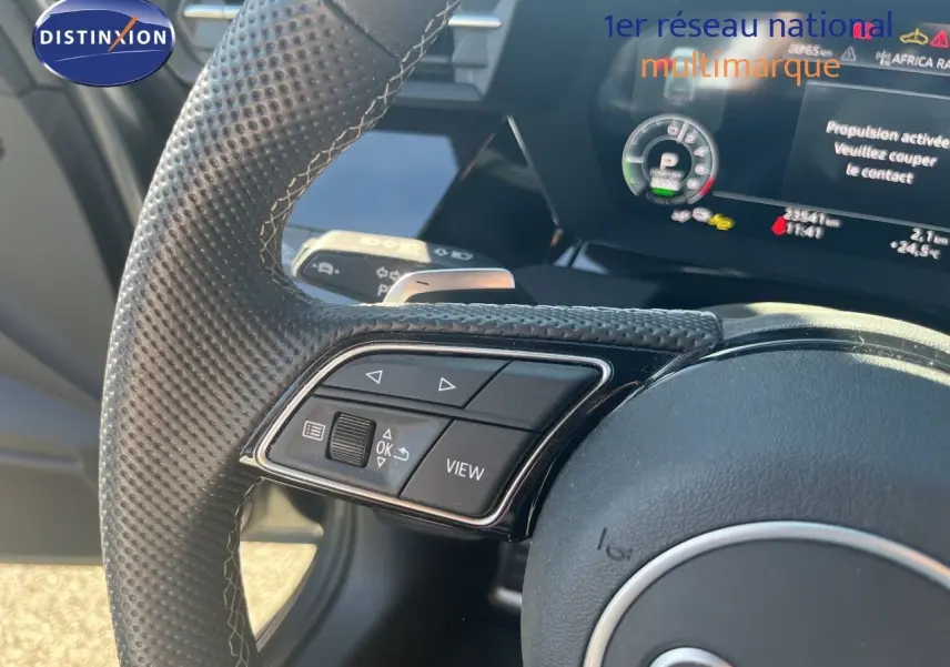 Gros plan sur le volant perforé et les commandes multifonctions de l'Audi A3 Sportback 40 TFSIe gris Daytona, intérieur noir.