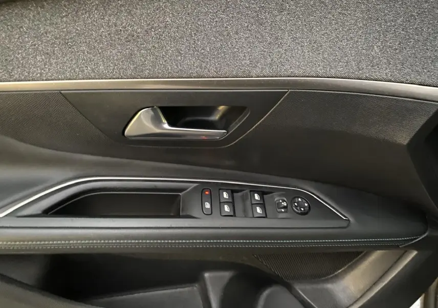 Détail de la porte côté conducteur du Peugeot 3008 gris Artense, avec commandes des vitres et rétroviseurs.