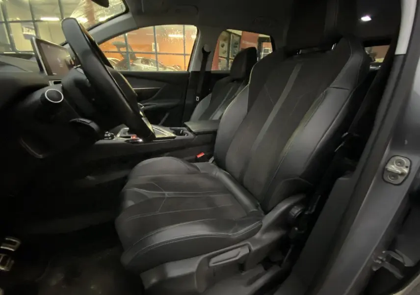 Vue intérieure côté conducteur du Peugeot 3008 gris Artense, mettant en valeur les sièges noirs et le tableau de bord.