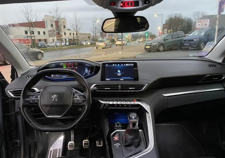Vue intérieure du tableau de bord et volant du Peugeot 3008 gris Artense, avec écran tactile et levier de vitesse manuel.
