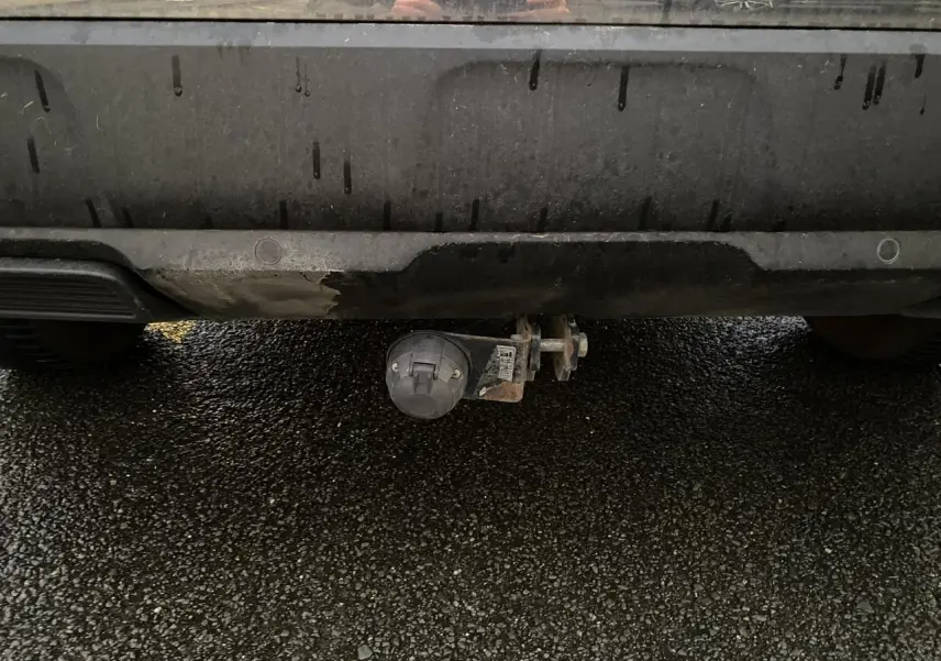 Prise électrique d'attelage sous le pare-chocs arrière d'un Peugeot 3008 gris Artense, vue centrée en gros plan.