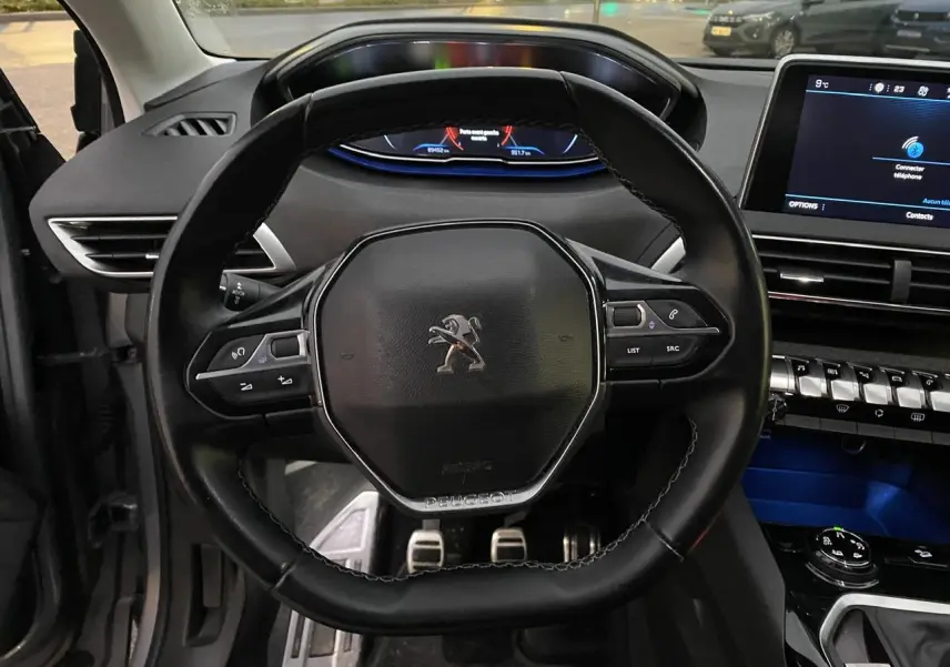 Vue rapprochée du volant cuir noir du Peugeot 3008 2019 avec tableau de bord digital et écran tactile central.
