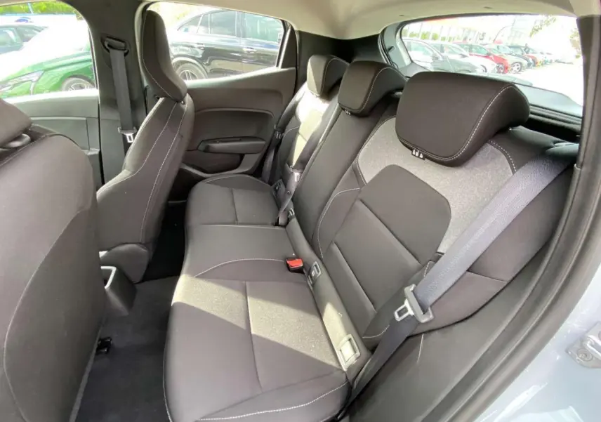 Vue intérieure arrière droite de la Renault Clio 2025 gris Rafale, montrant les sièges arrière en tissu noir avec surpiqûres blanches.