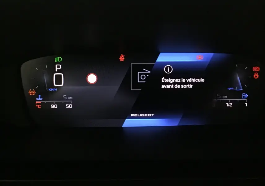 Tableau de bord numérique de Peugeot 308 gris Sellenium, affichant un message d'arrêt du véhicule avant de sortir.