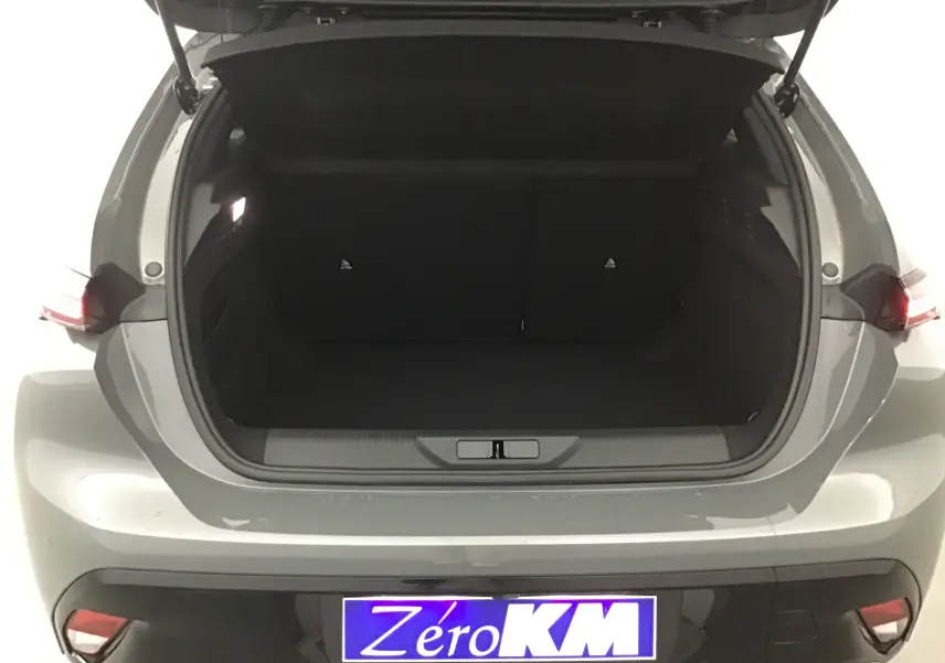 Coffre ouvert vu de l'arrière d'une Peugeot 308 gris Sellenium, montrant l'espace de chargement vide.
